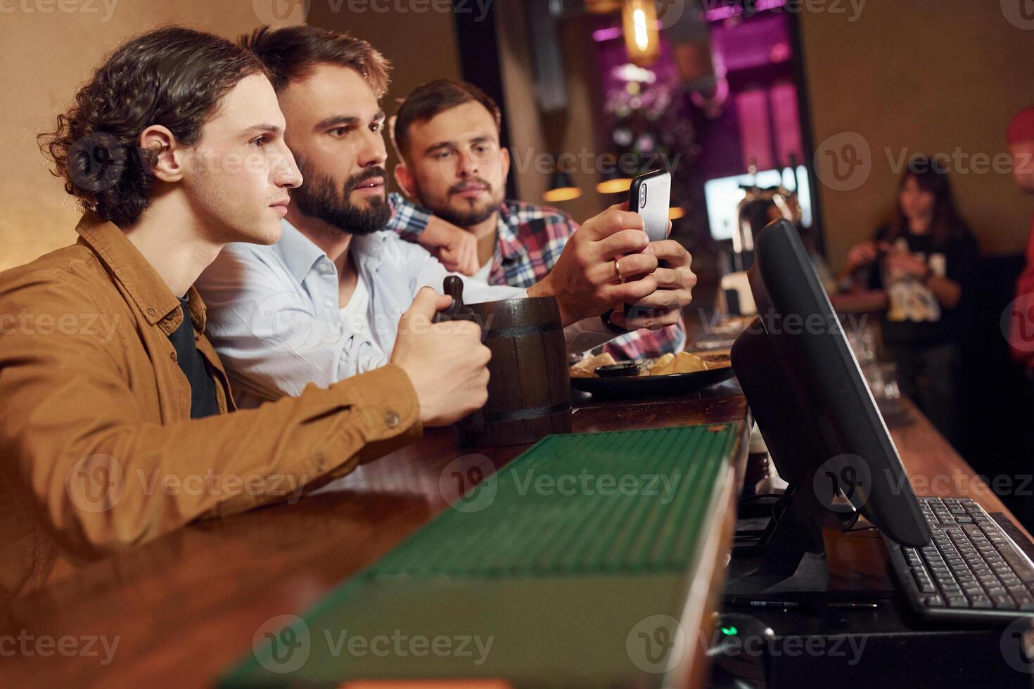 Sitting by the table. Three, friends are in the bar,drinking beer and having a good time photo