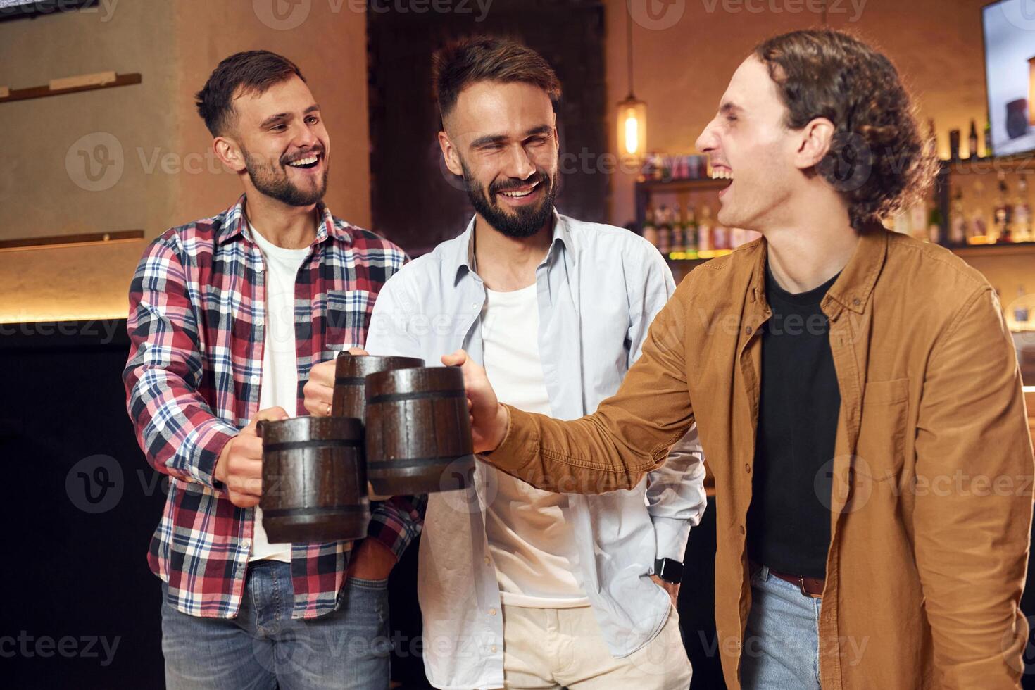 Standing and smiling. Three friends are in the bar drinking beer and having a good time photo