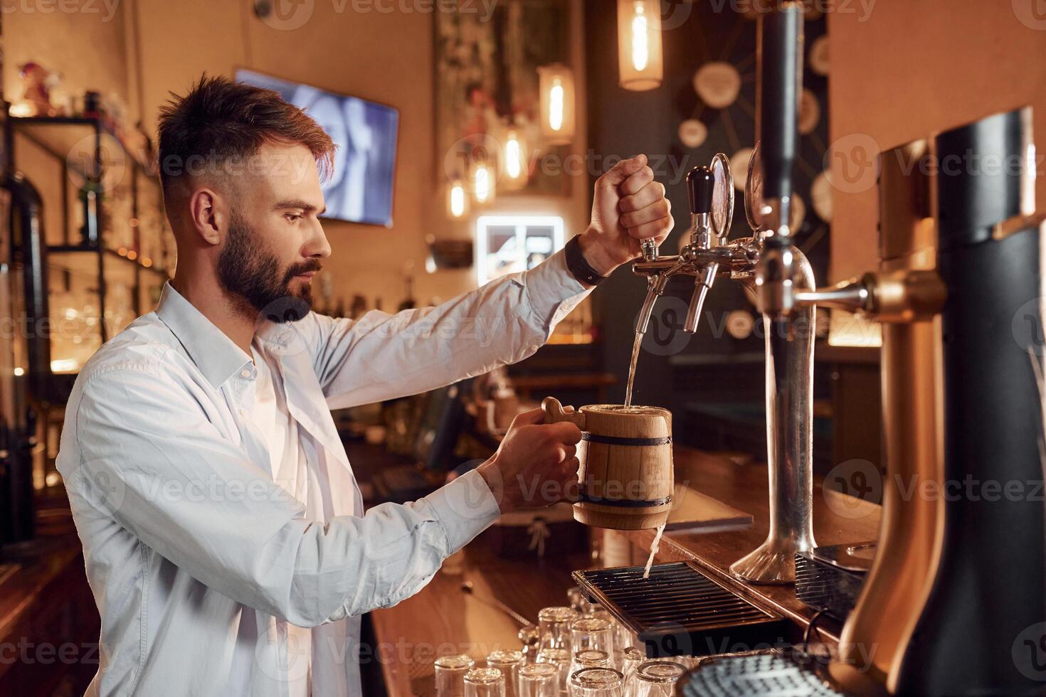 Bartender pours, ,beer. Man is working in the bar photo