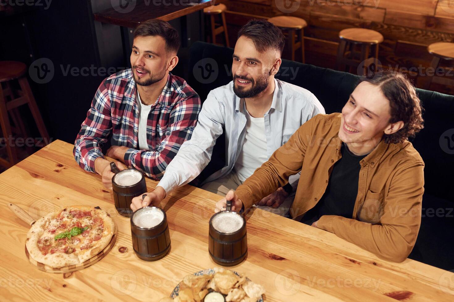 Top,, view. Sitting by the table. Three friends are in the bar drinking beer and having a good time photo