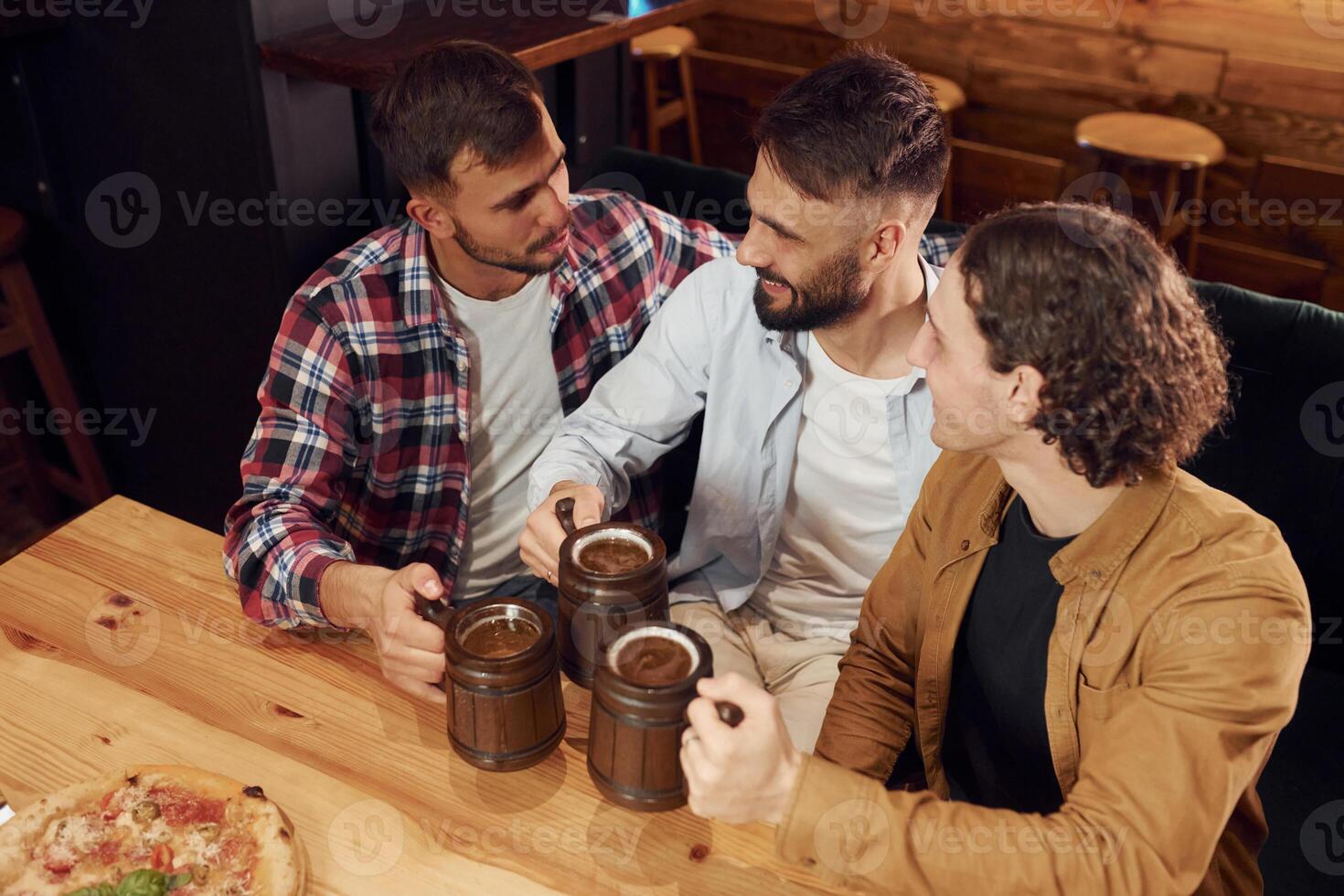 Top view.. Sitting by the table. Three friends are in the bar drinking beer and having a good time photo