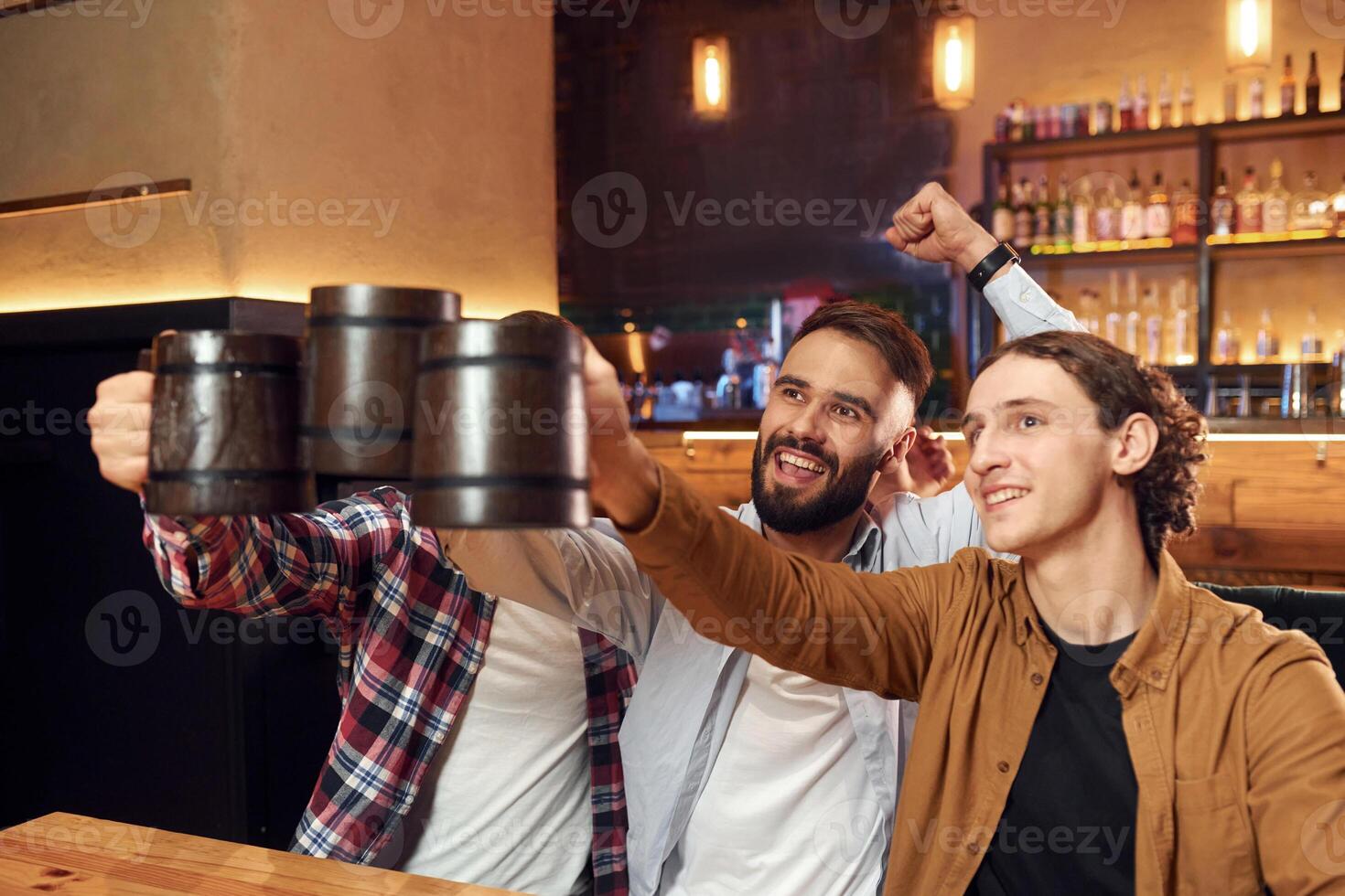 Soccer, fans ,watching match. Three friends are in the bar drinking beer and having a good time photo