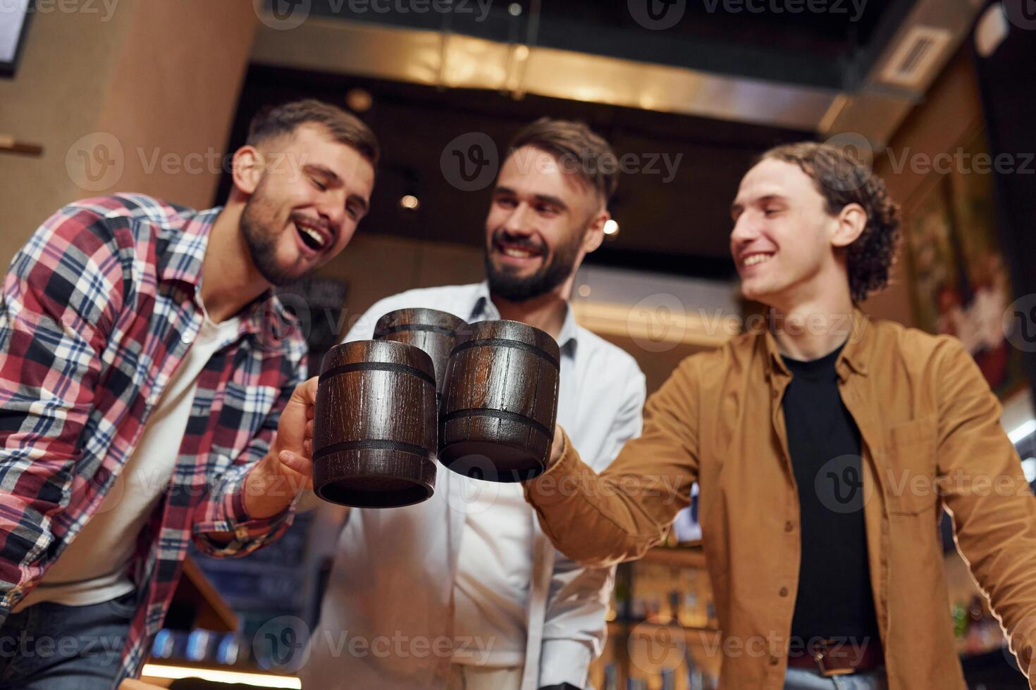 Knocking, the mugs. Three friends are in the bar drinking beer and having a good time photo