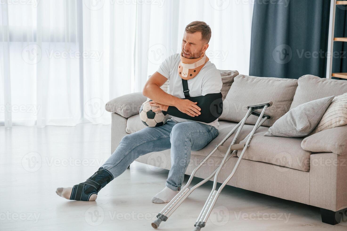 Pain, in the arm. Man with crutches is at home indoors. Having injuries photo