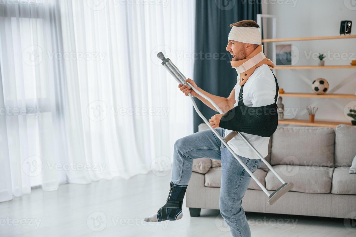 Pretending of ,playing guitar on crutches. Man is at home indoors. Having injuries photo