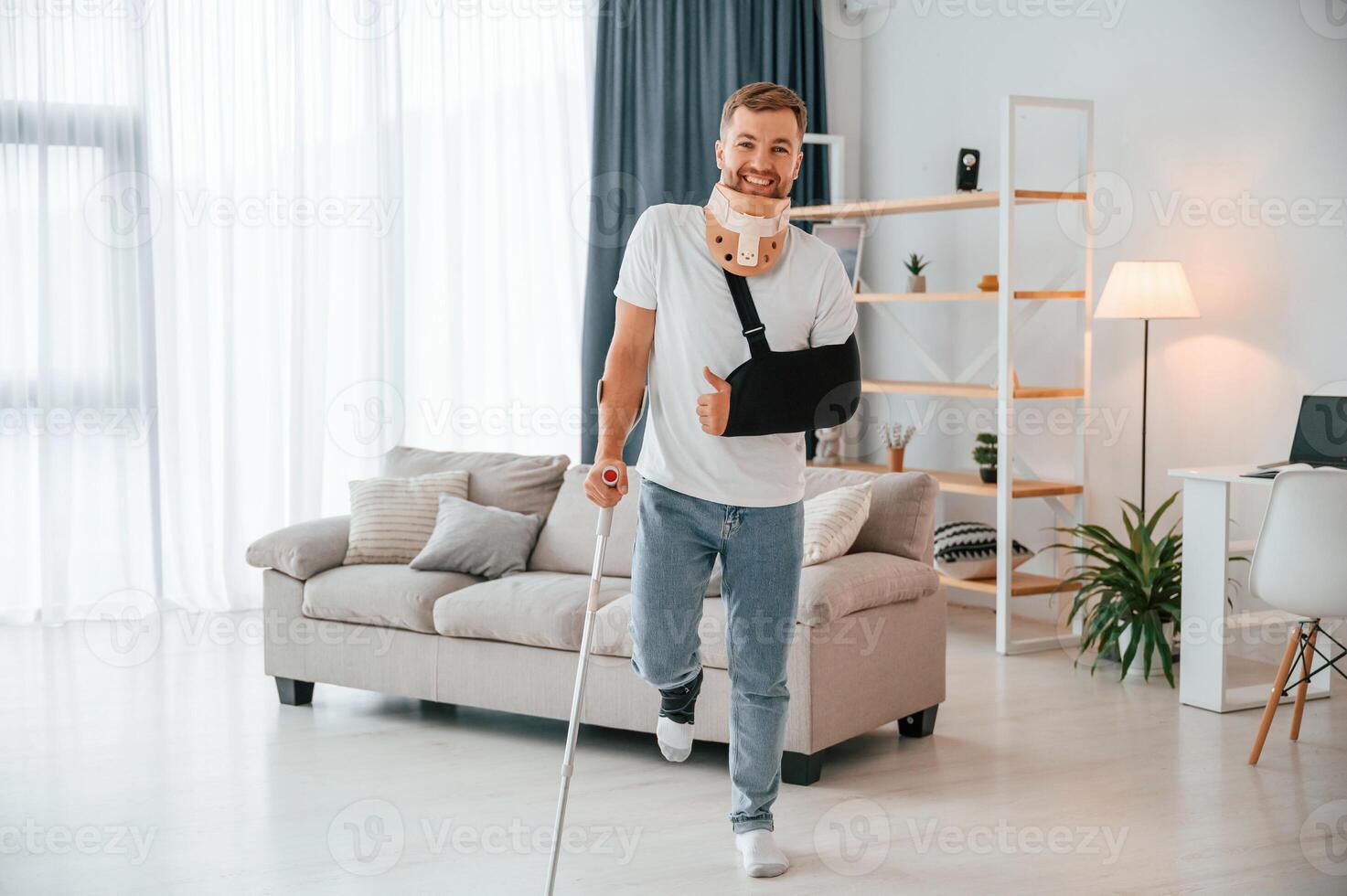 Standing and smiling.. Man with ,crutches is at home indoors. Having injuries photo