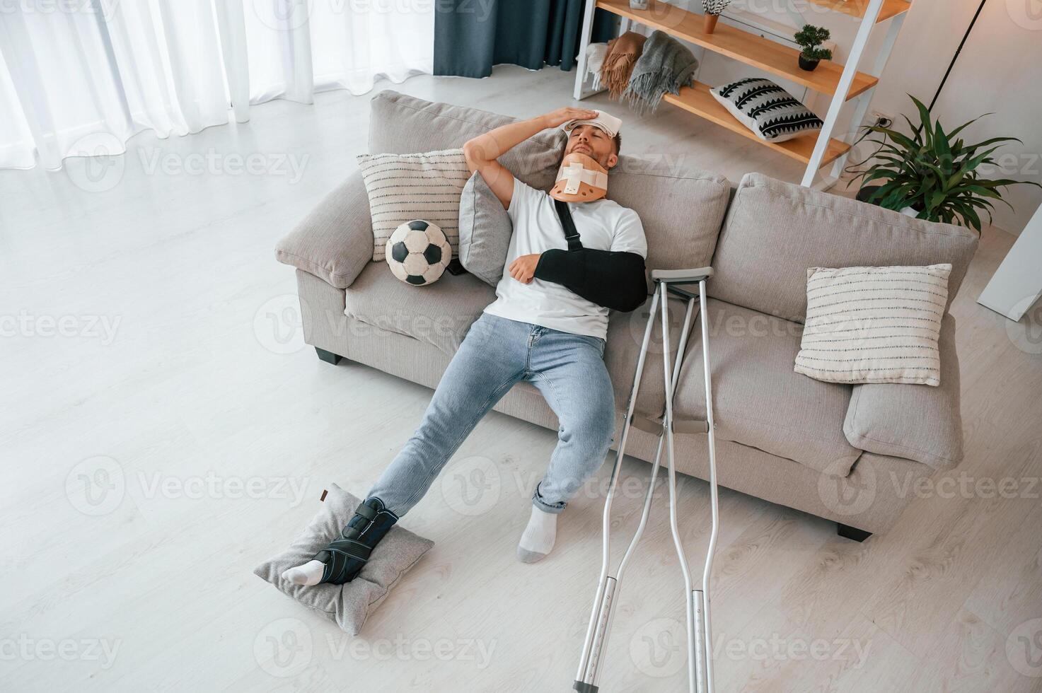 Laying down ,and suffering from the pain. Man with crutches is at home indoors. Having injuries photo