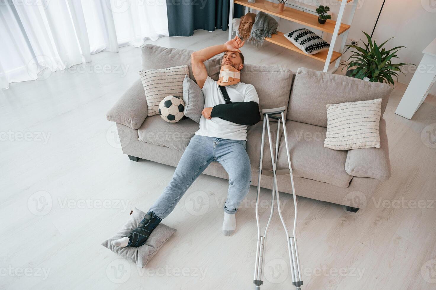 Laying ,down and suffering from the pain. Man with crutches is at home indoors. Having injuries photo