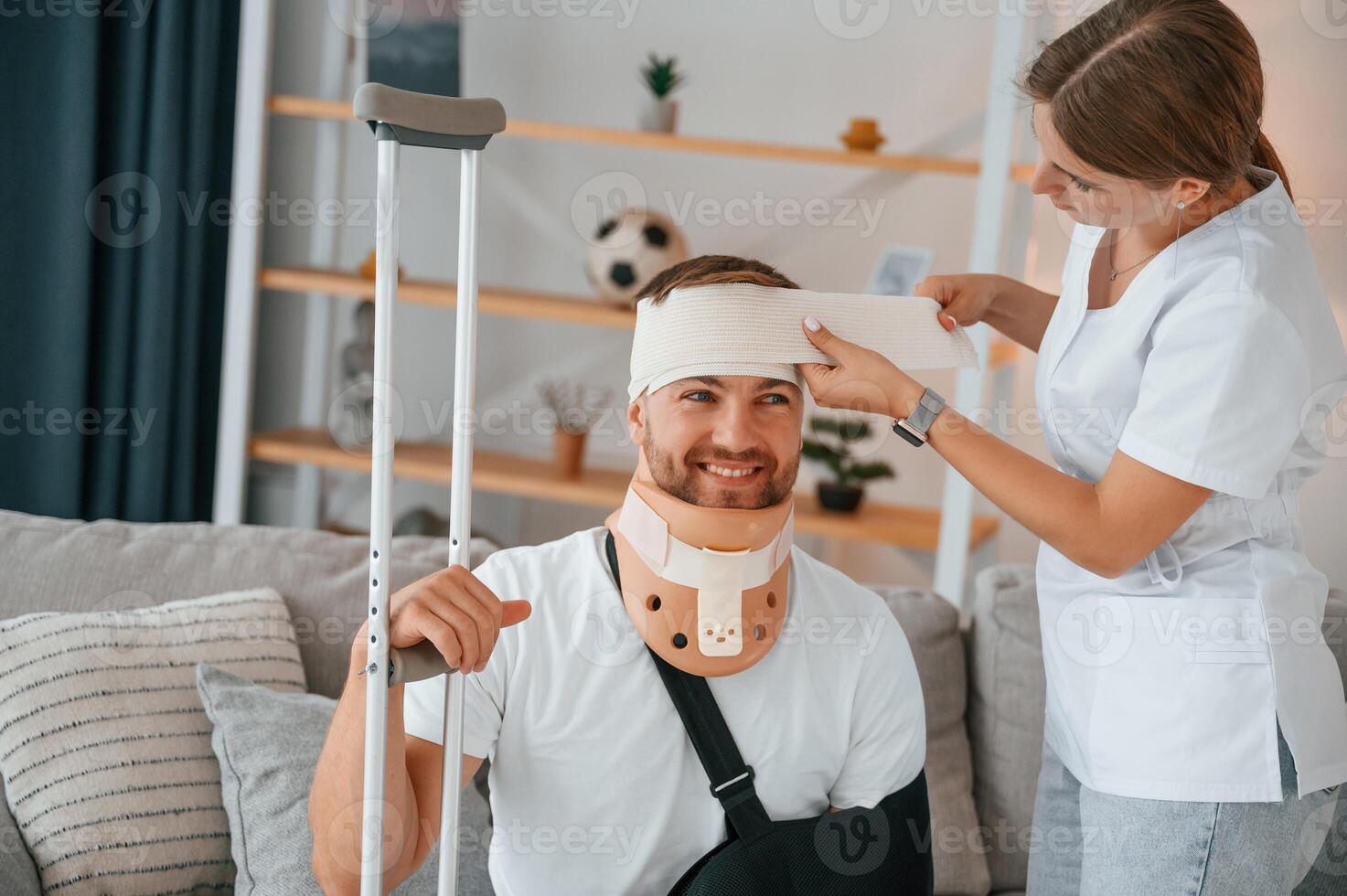 Taking, care ,of bandage on the head. Woman is helping injured man at home photo