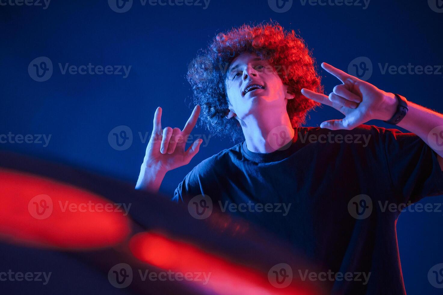 Dj is ,playing music from vinyl. Young man with curly hair is indoors illuminated by neon lighting photo