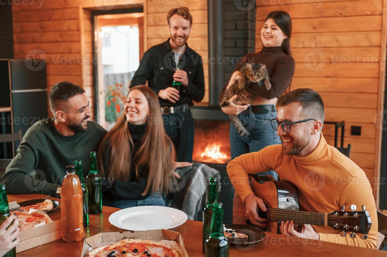 Sitting by, the table with pizza and beer. Group of friends is having good weekend indoors photo