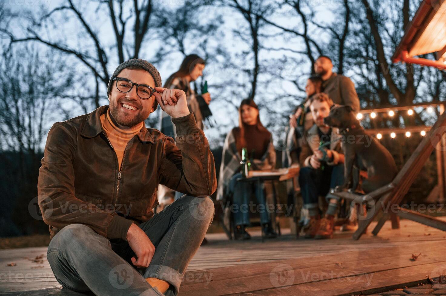 Man is smoking. Group of people is spending time together on the backyard at evening time photo