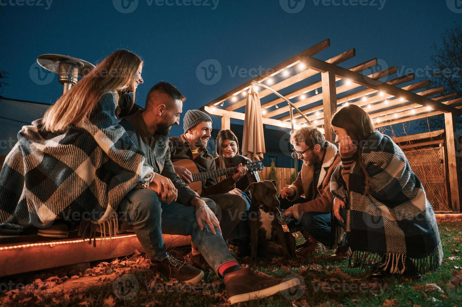 Having fun with dog. Group ,of people is spending time together on the backyard at evening time photo