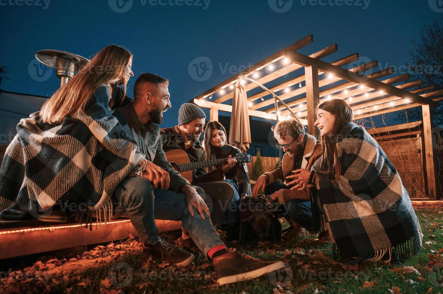 Having ,fun with dog. Group of people is spending time together on the backyard at evening time photo
