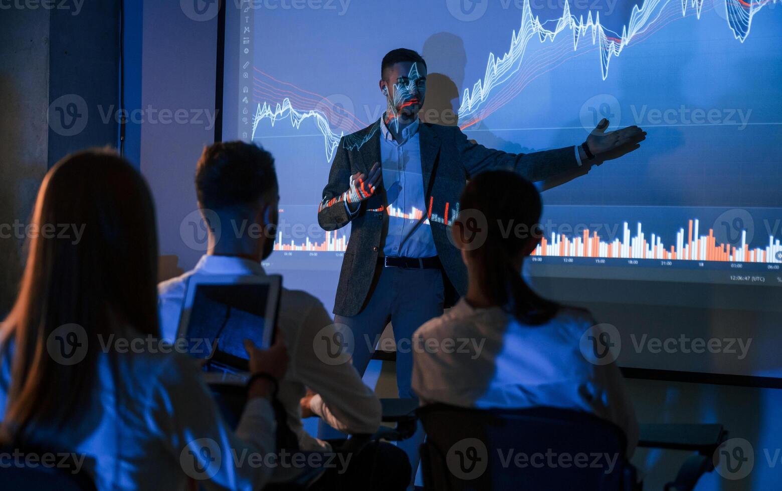 Broker, is showing the plan on projecto.. Male leader talking to employees in office of stock exchange company photo