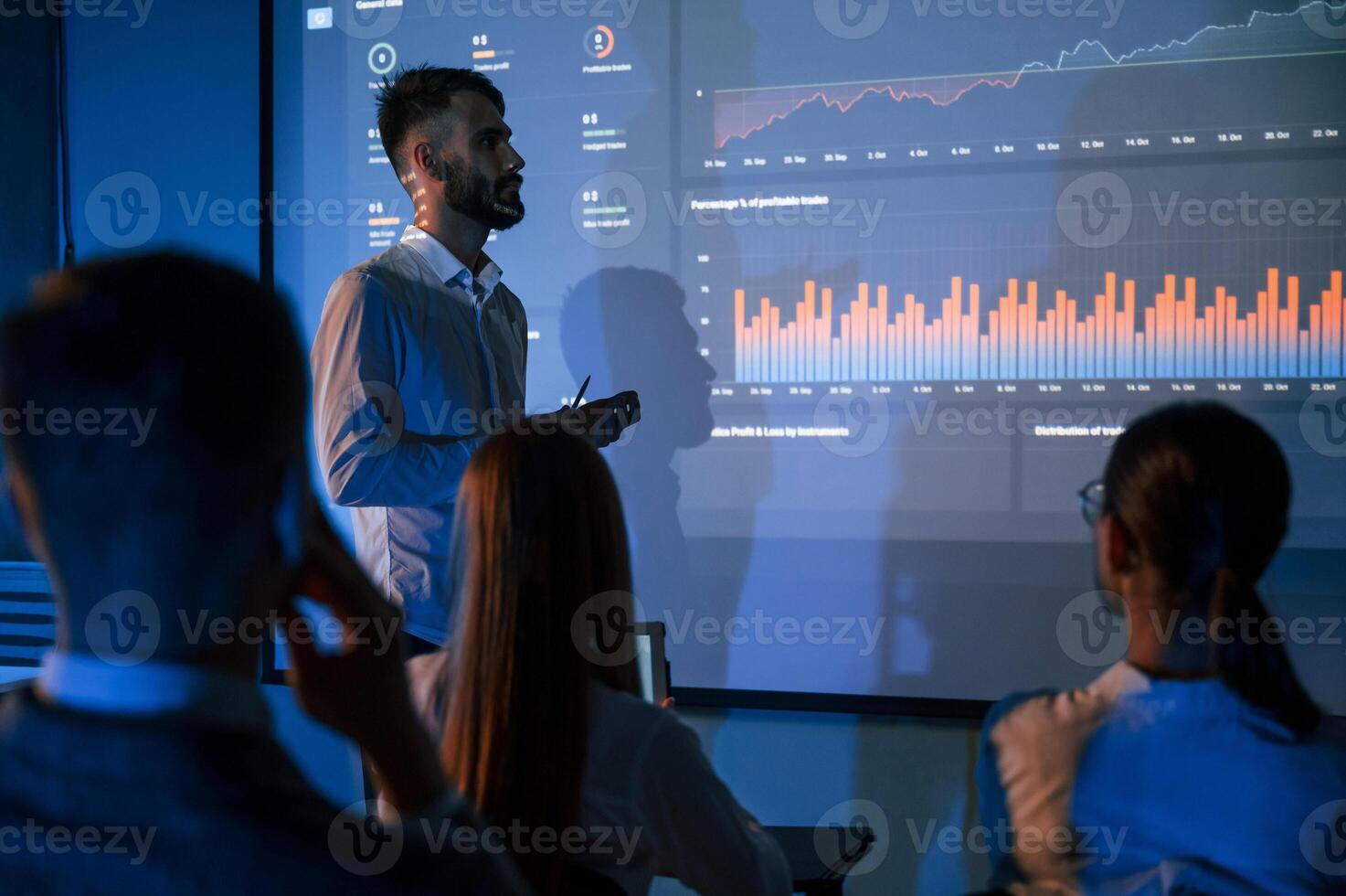 Male leader talking ,to employees, showing the plan on the projector in office of stock exchange company photo