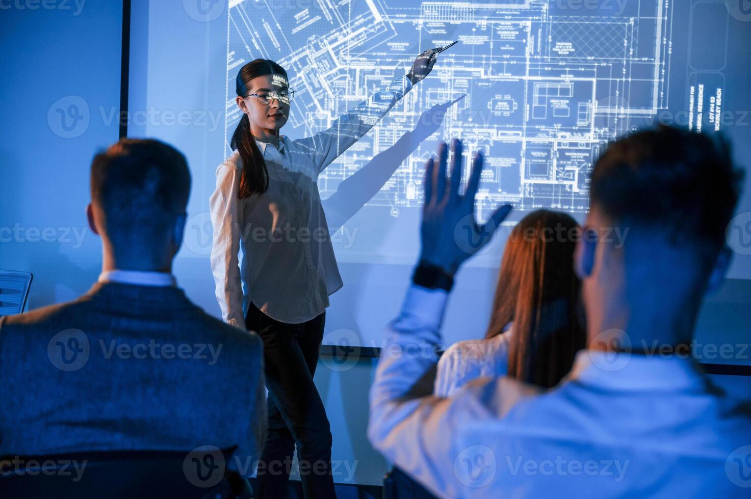 Female, leader, talking to employees, showing the plan on the projector in office of stock exchange company photo