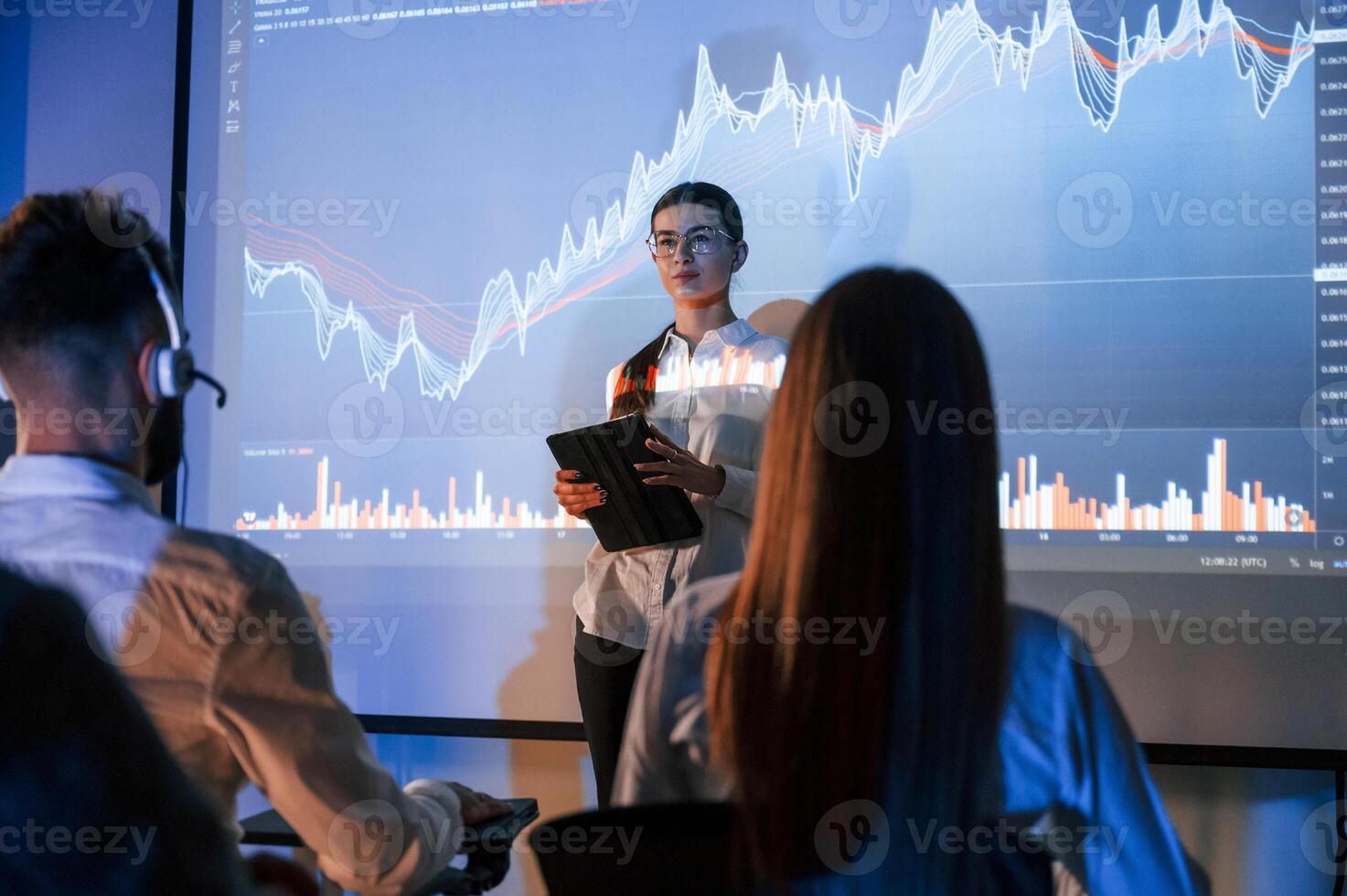 Exchange ,company. Female, leader talking to employees, showing the plan on the projector in office of stock photo