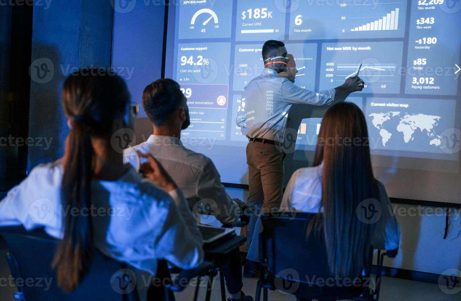 Showing information by, the hand. Male leader talking to employees, the projector in office of stock exchange company photo