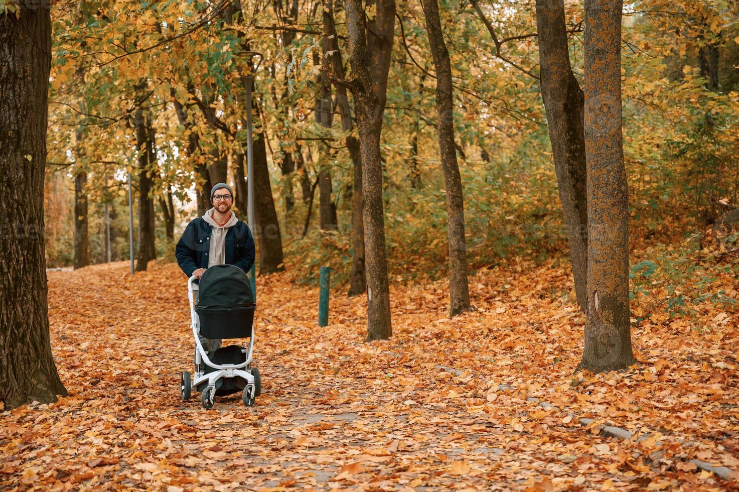 Enjoying the, nature. Man with pram is having a walk in the autumn park photo