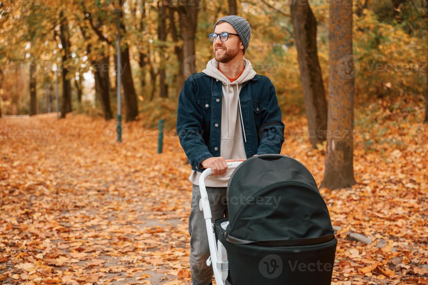 Enjoying the nature. Man, with pram is having a walk in the autumn park photo