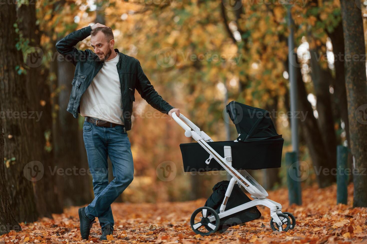 Man ,with pram is having a walk in the autumn park photo