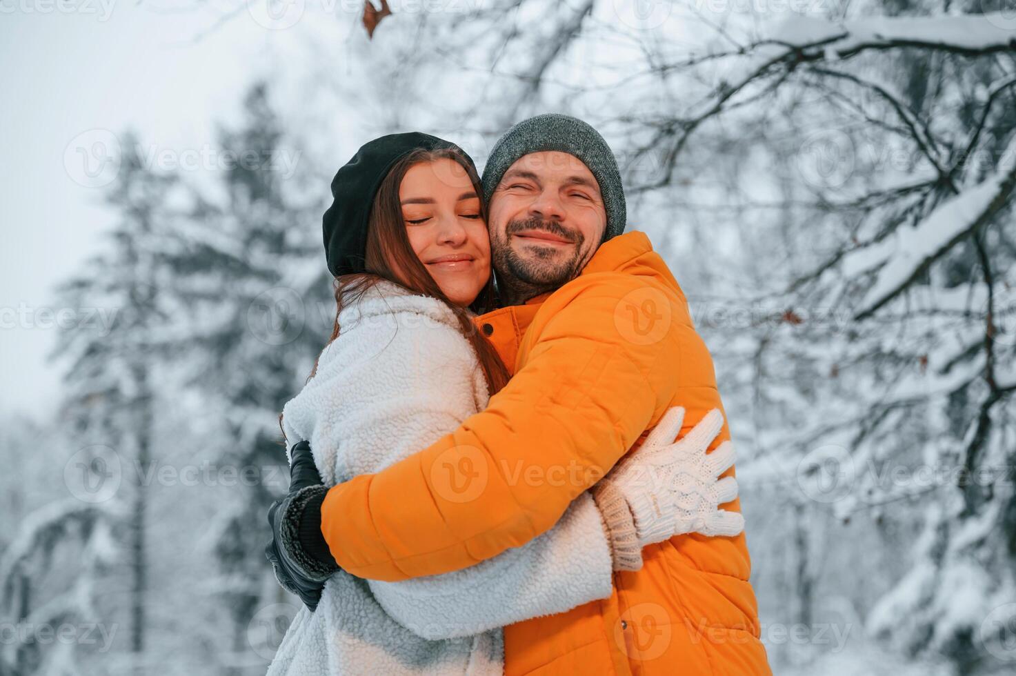 Lovely, couple embracing each other while standing in the winter forest photo