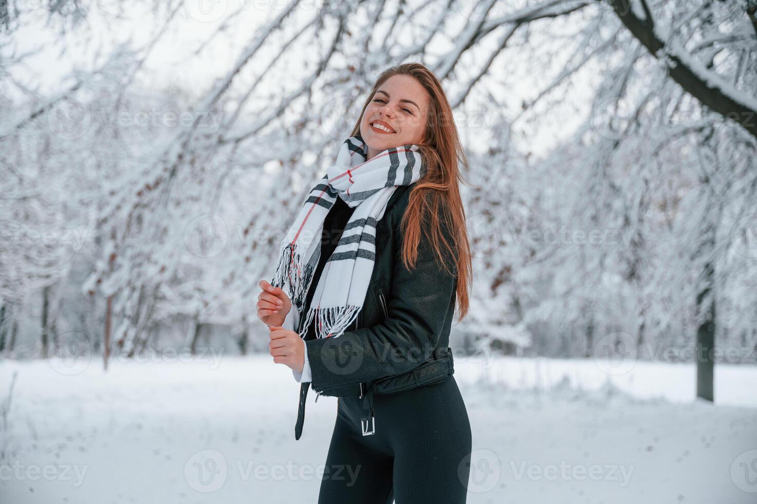 In the warm scarf... Beautiful young woman is outdoors in the winter forest photo