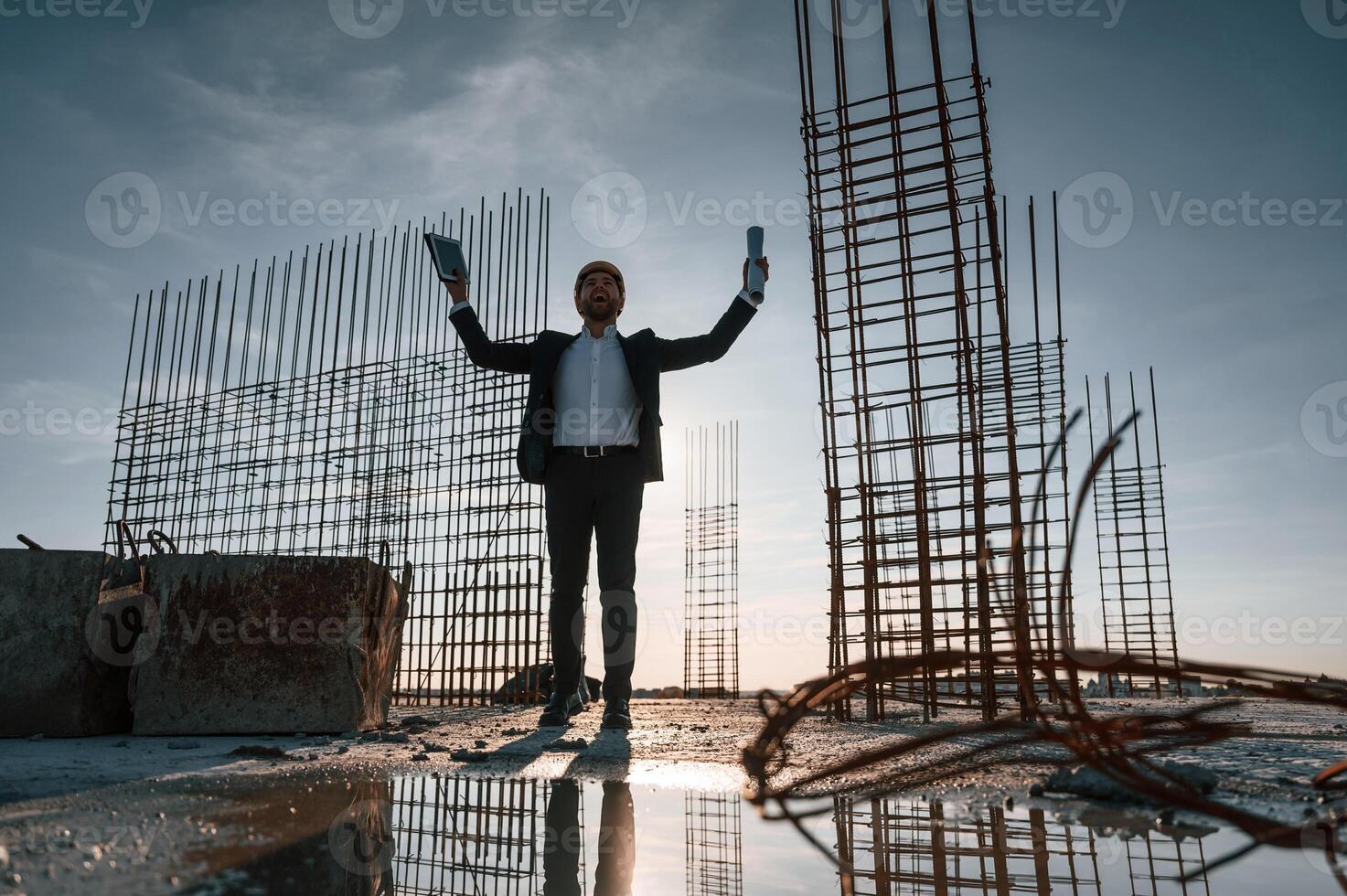 With hands up. Standing at evening time. Businessman in formal clothes is on the construction site photo