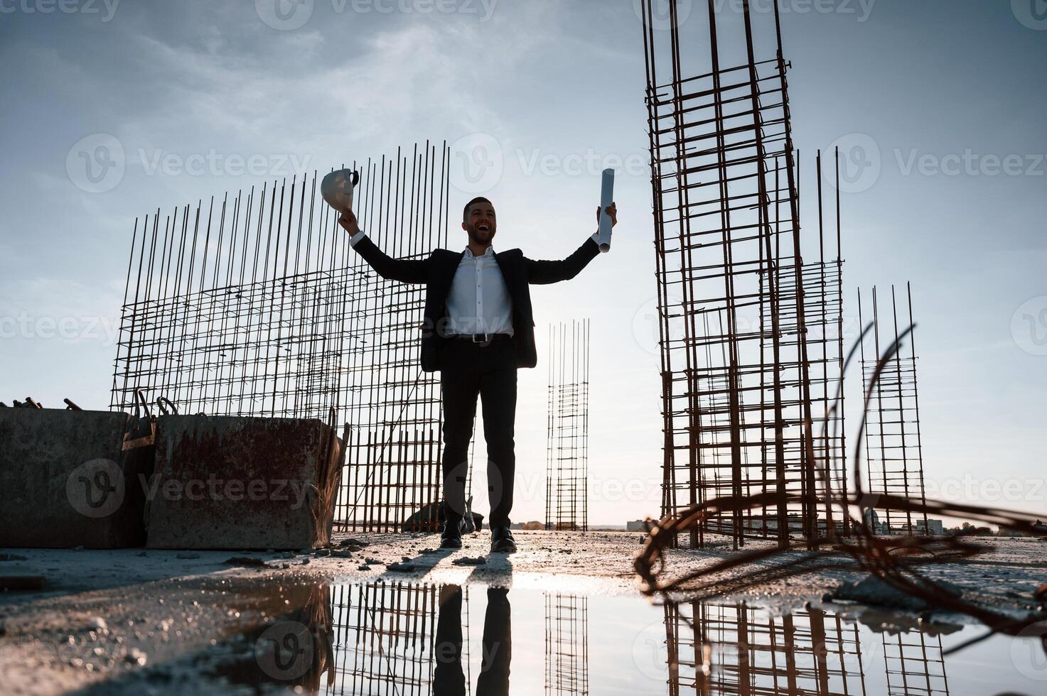 With, hands up. Standing at evening time. Businessman in formal clothes is on the construction site photo