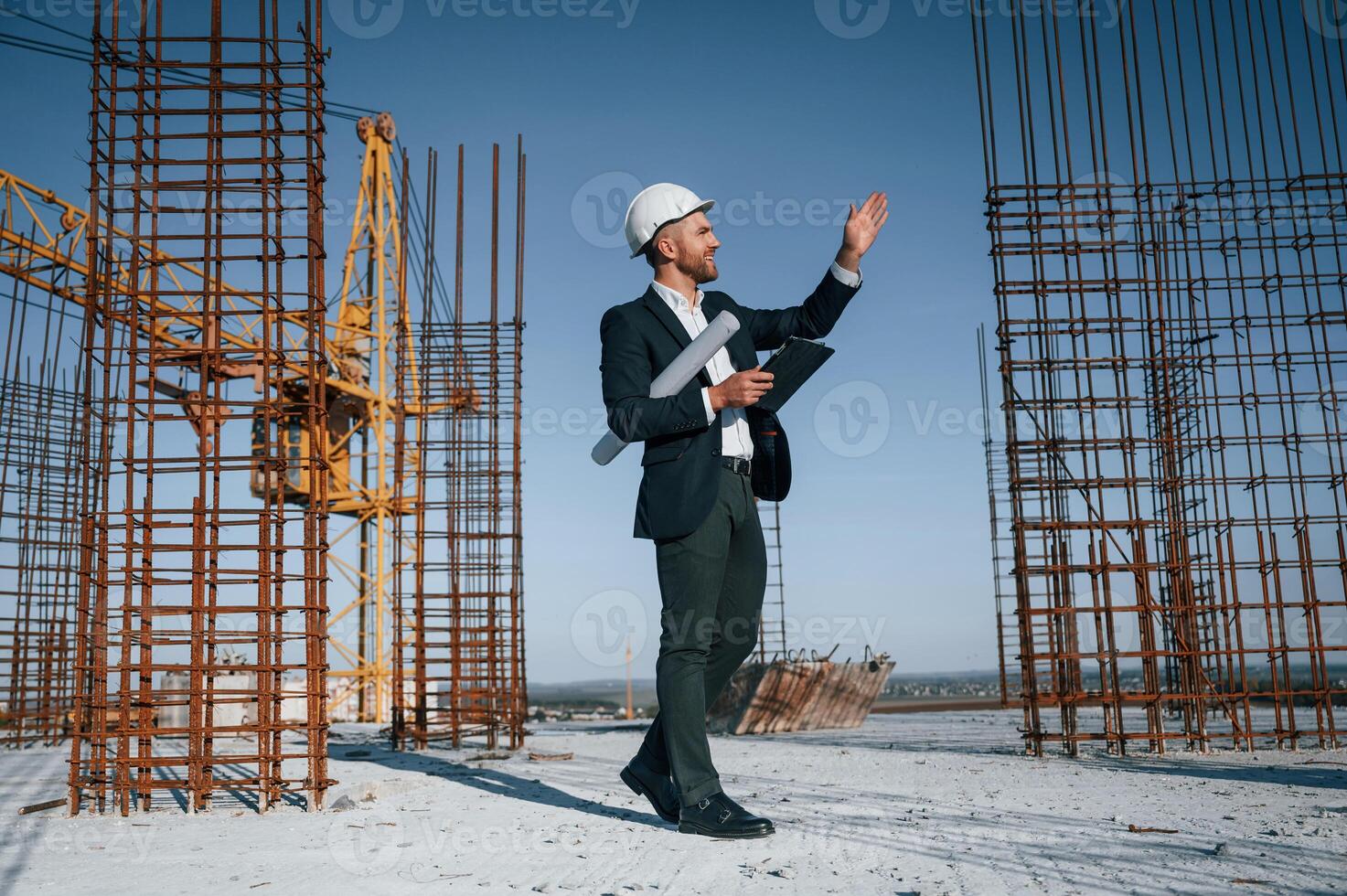 Standing and ,holding, digital tablet. Businessman in formal clothes is on the construction site at daytime photo