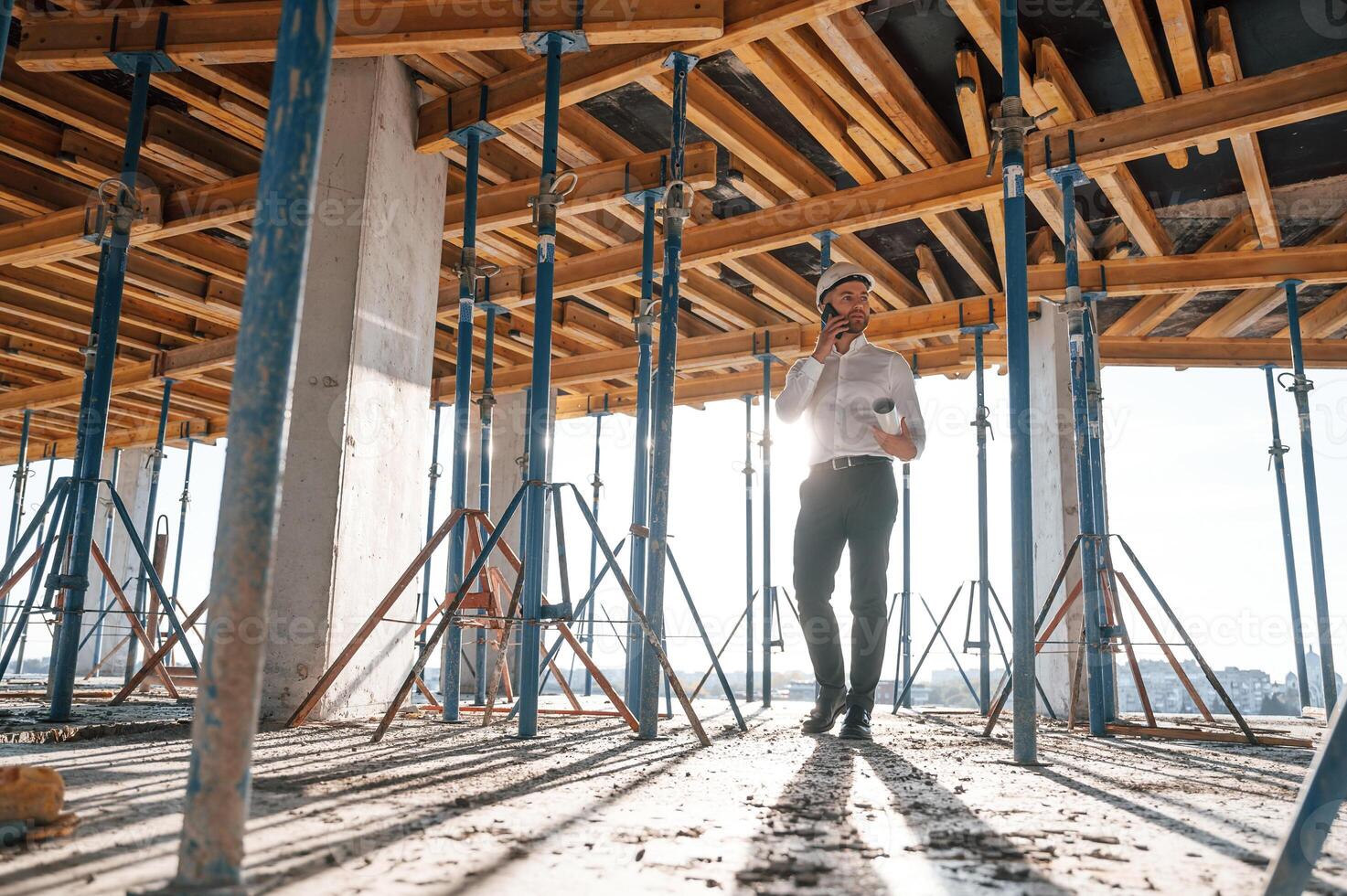 Beautiful, sunlight. Walking with, plan in hands. Man is working on the construction site at daytime photo