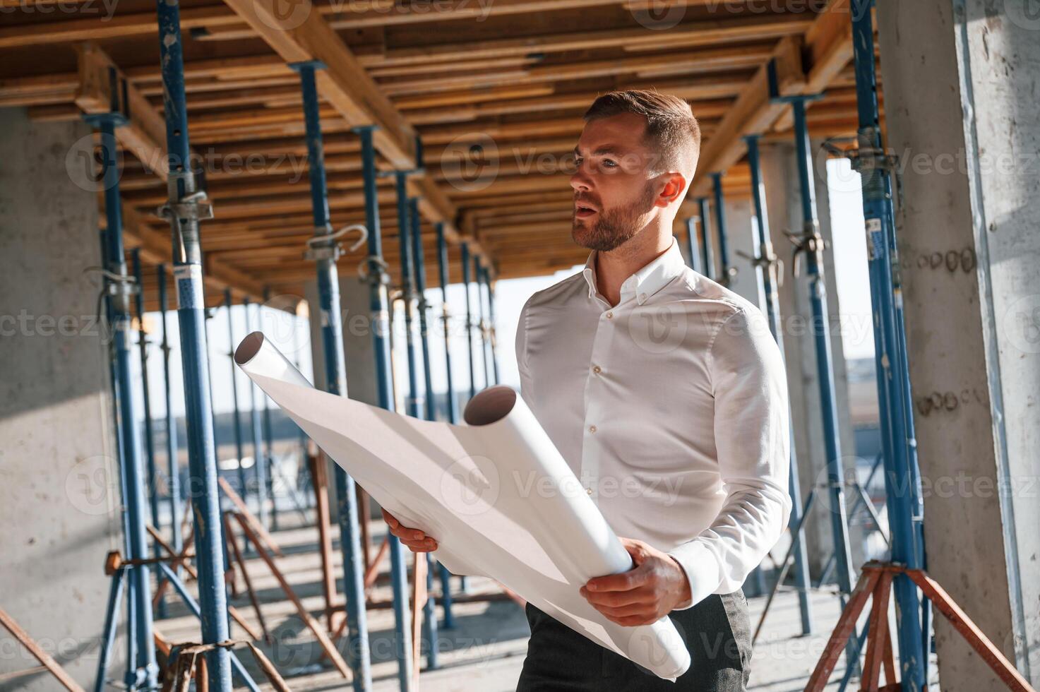 Standing and reading plan.. Man is working on the construction site at daytime photo