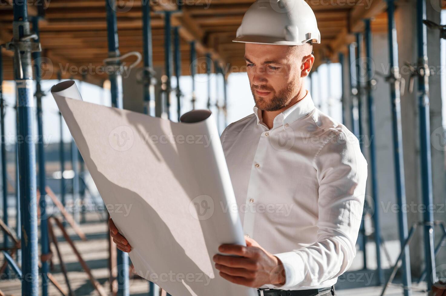 Standing and reading plan.. Man ,is working on the ,construction site at daytime photo