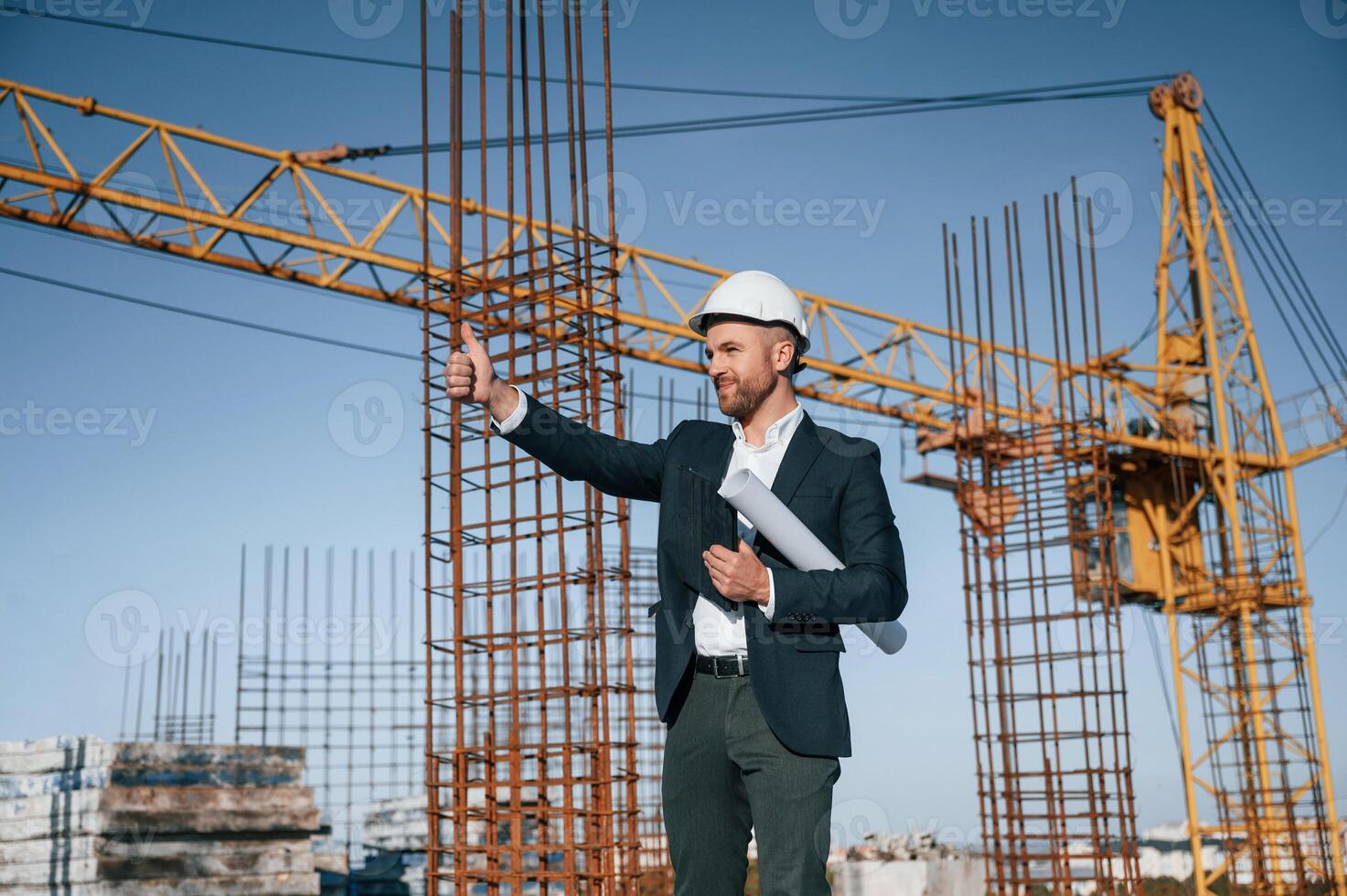 Showing thumb, up.. Businessman in formal clothes is on the construction site at daytime photo