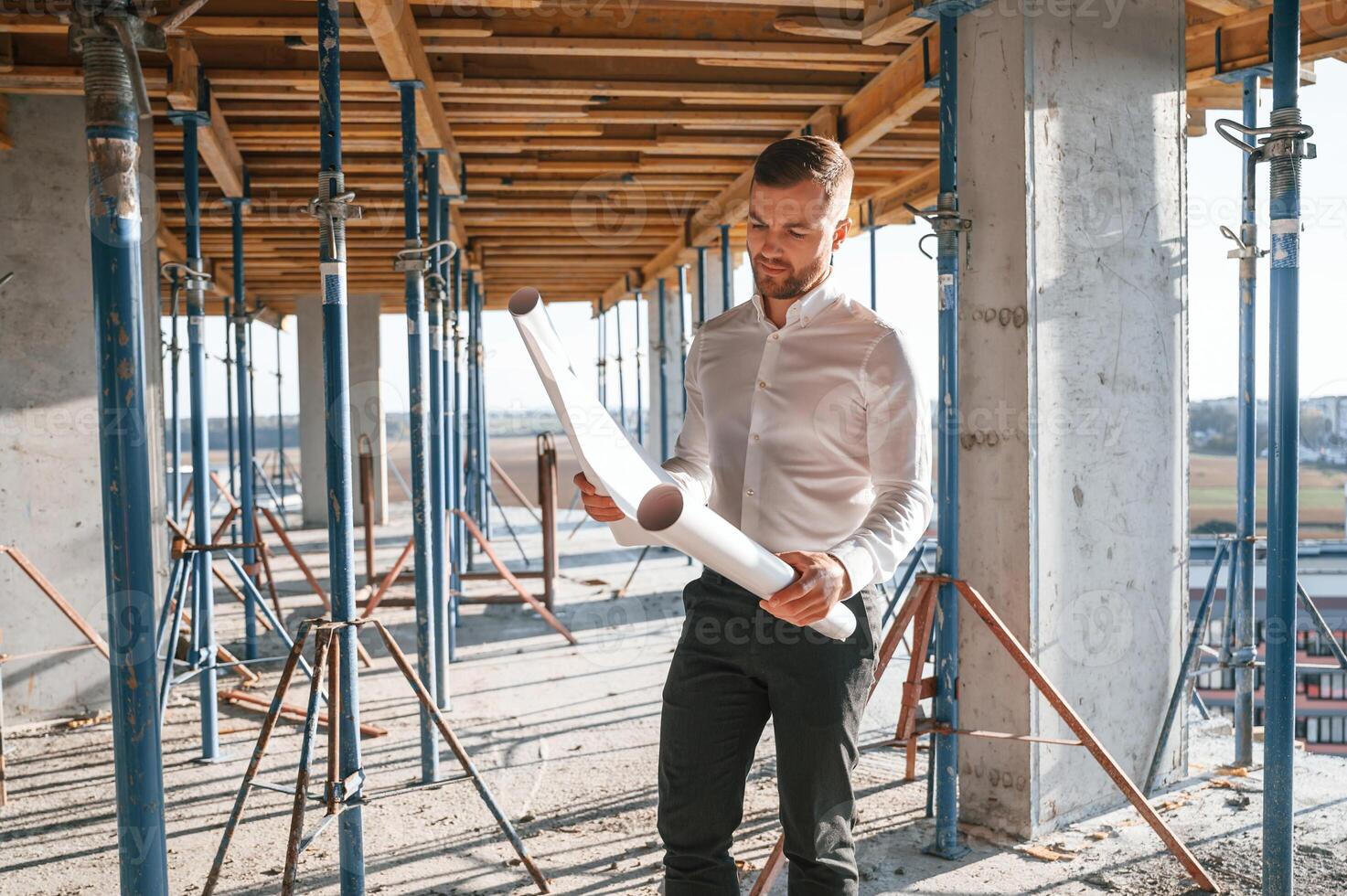 Standing and reading plan.. Man ,is working, on the construction site at daytime photo