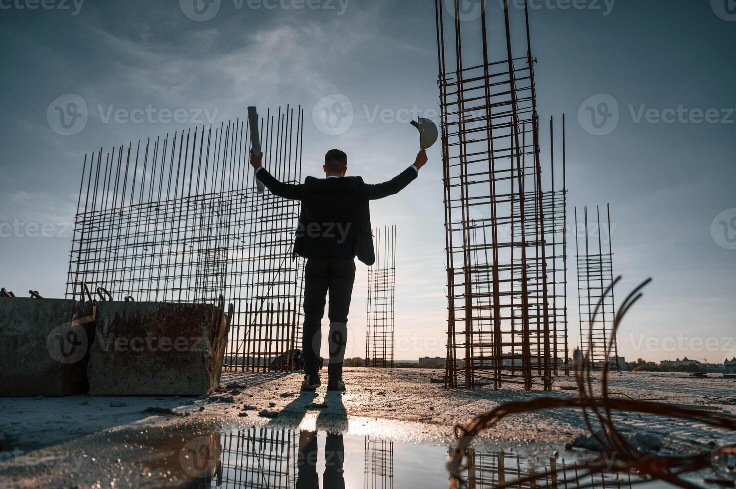 With ,hands up.. Standing at evening time. Businessman in formal clothes is on the construction site photo