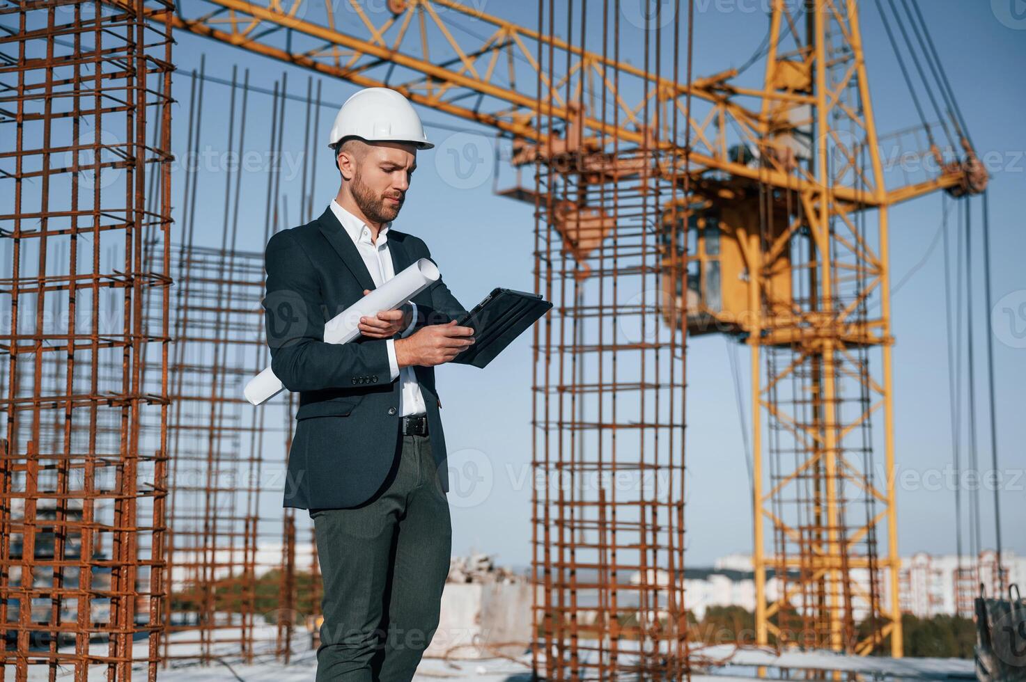 Standing and holding digital tablet.. Businessman in formal clothes is on the construction site at daytime photo