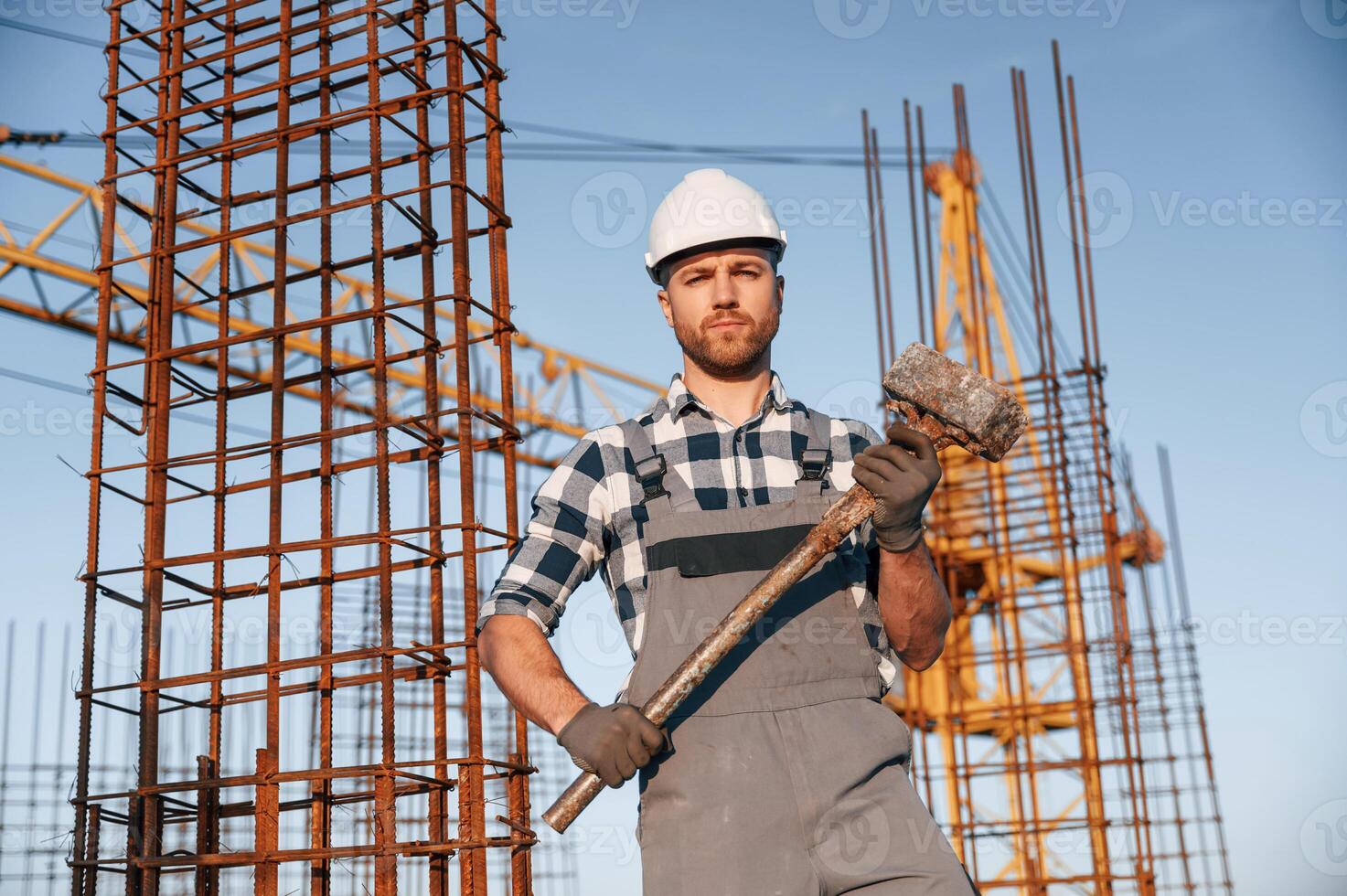 With big hammer ,in, hands. Man is working on the construction site at daytime photo
