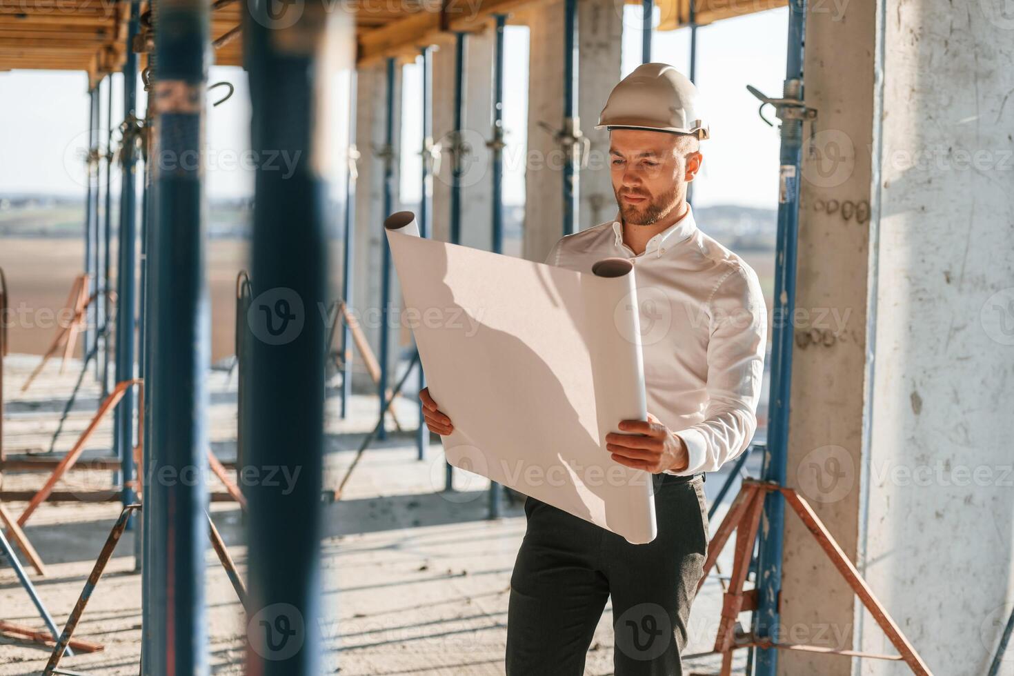 Manager is in the formal clothes.. Holding plan i,n hands. Man is working on the construction site at daytime photo