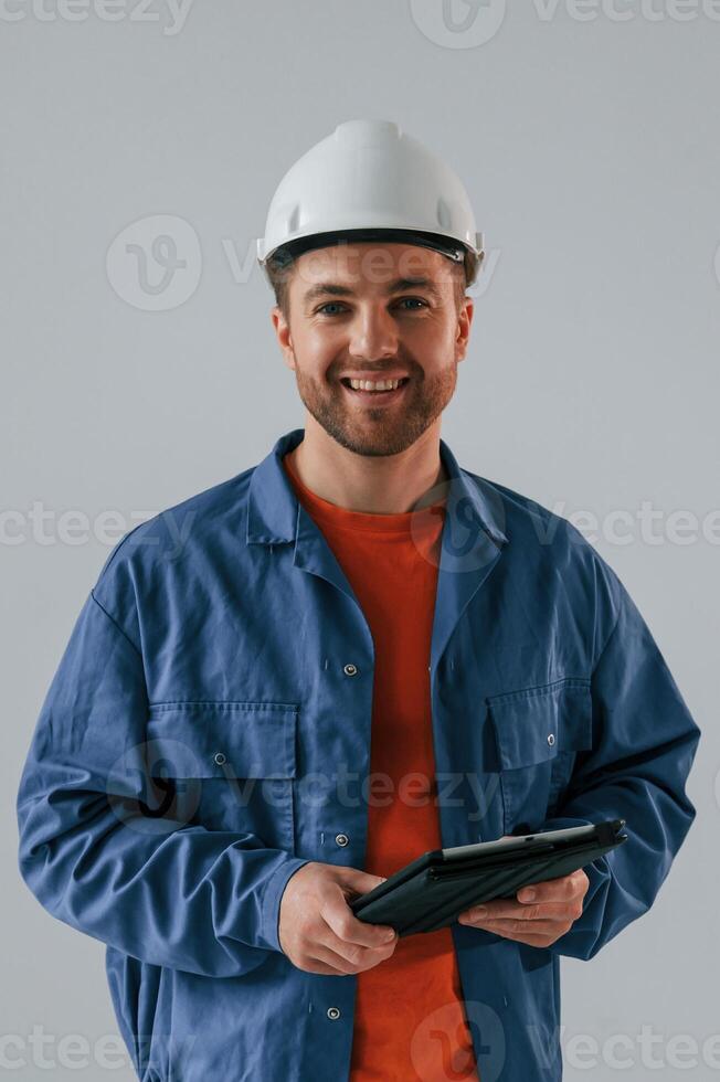 Construction worke,r in hard hat is with tablet. Handsome man is in the studio against white background photo