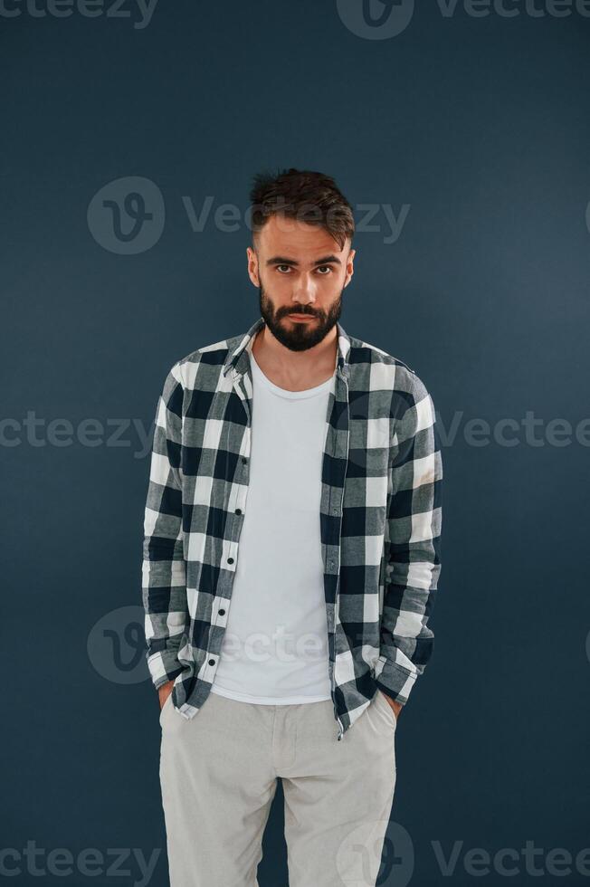 In, a checkered ,shirt. Handsome man is in the studio against blue background photo
