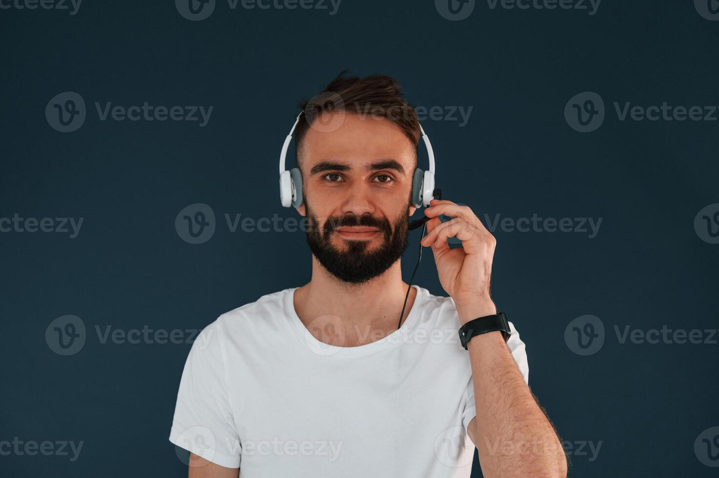 In headphones. Handsome man is ,in the studio against blue background photo