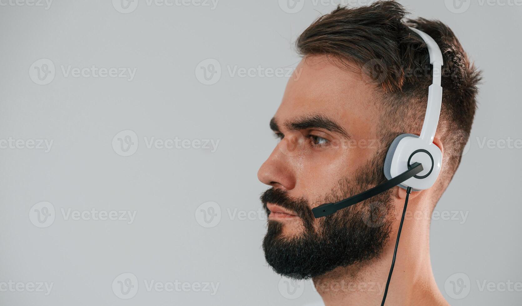 Side view. In headset. Handsome man is in the, studio against white background photo