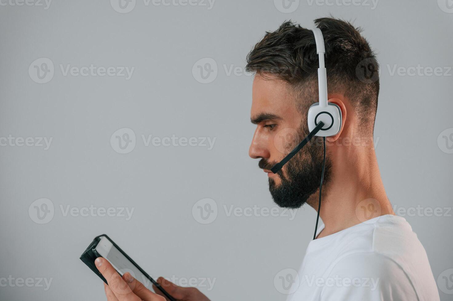 Side view. In headset. Handsome, man is in the studio against white background photo