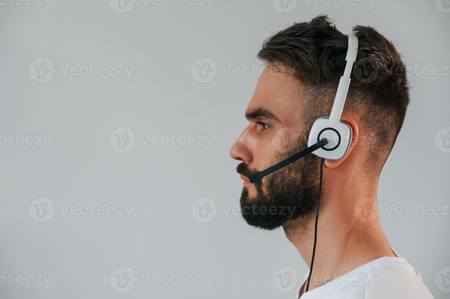 Side view. In ,headset. Handsome man is in the studio against white background photo