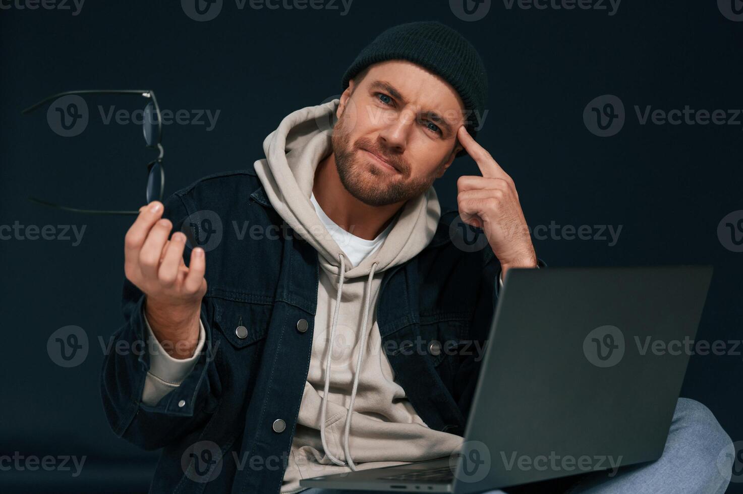 Sitting and using laptop.. Handsome man is in the studio against background photo