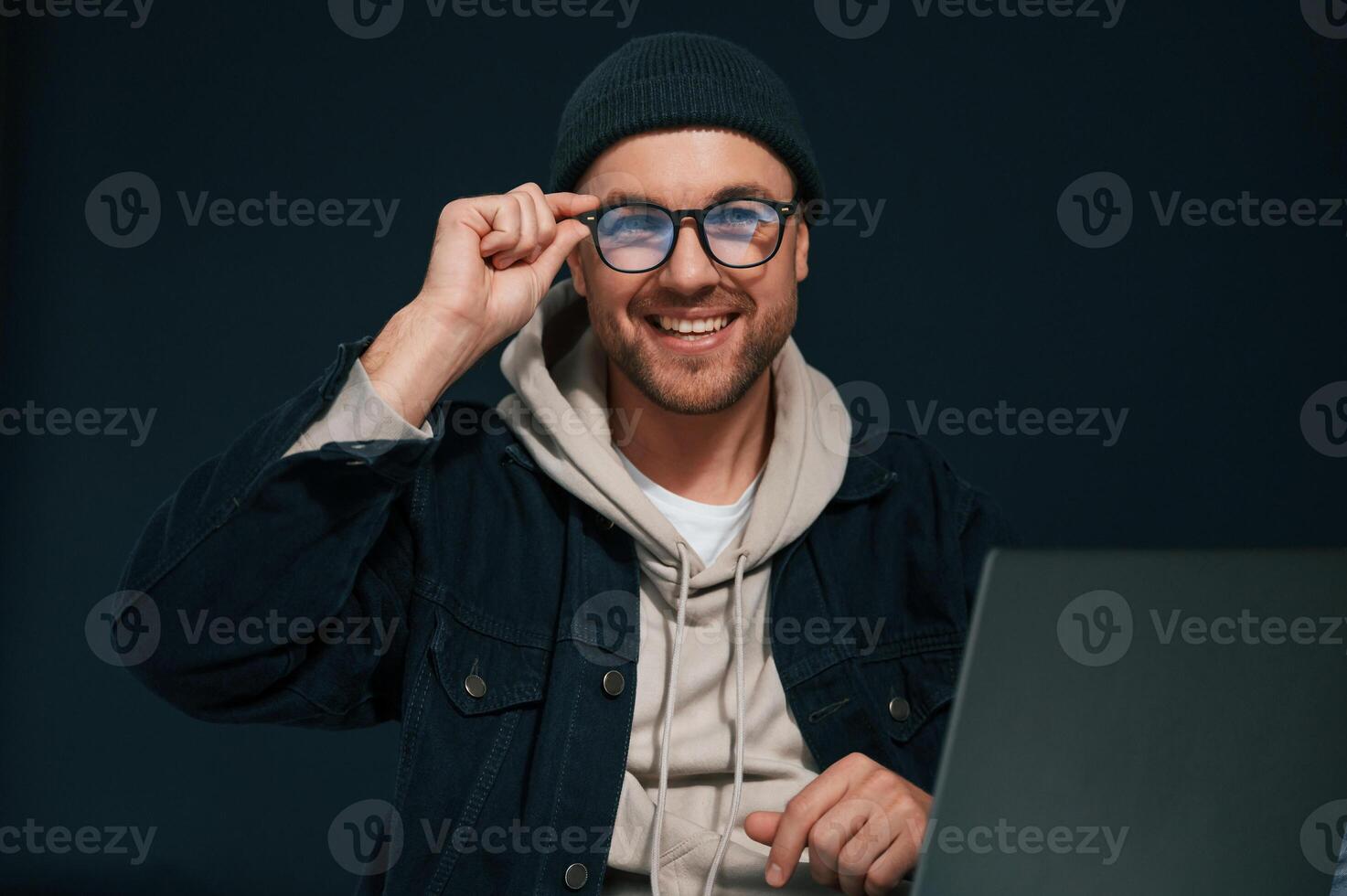 Smiling ,and sitting by laptop. Handsome man is in the studio against background photo