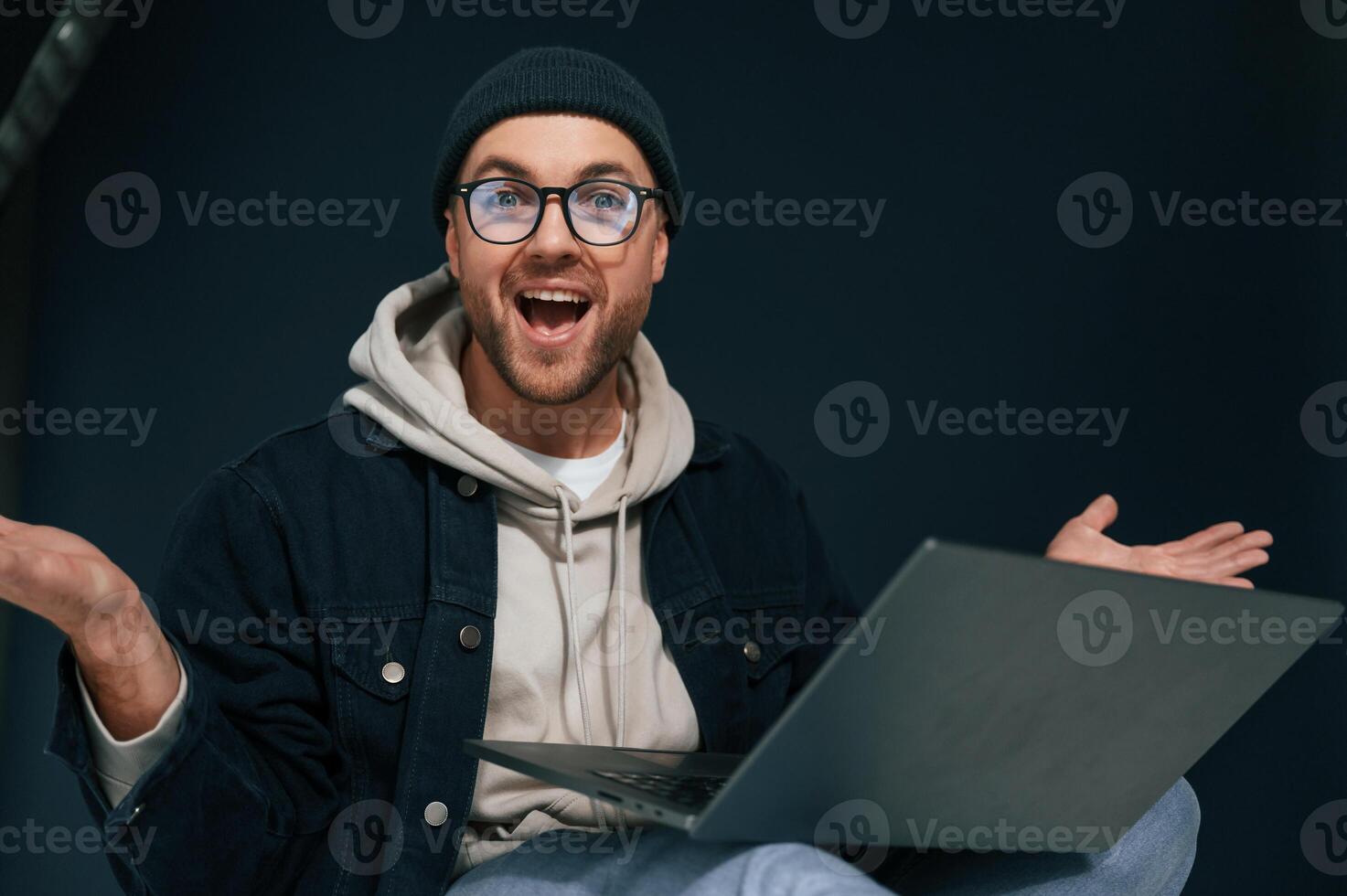 Celebrating ,success. Feeling ,uplifting. Using laptop. Handsome man is in the studio against background photo