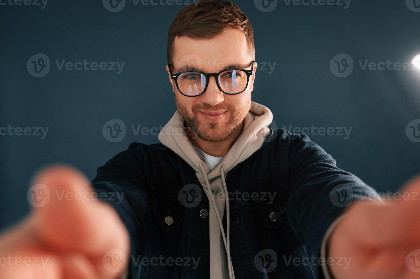 Making selfie. Handsome man is in the studio against blue background photo